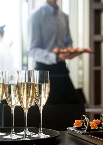 A table of champagne flutes beside a man in a suit.