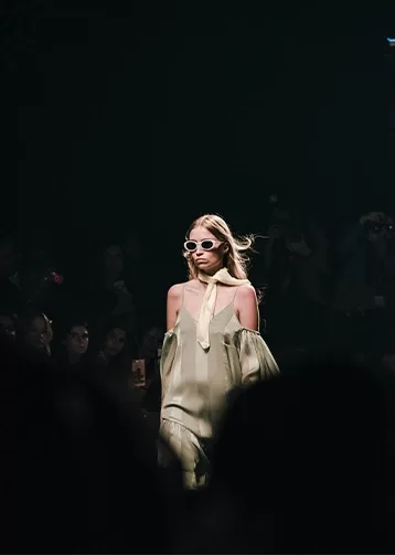 A model walking on a runway lit up by the stage lights.