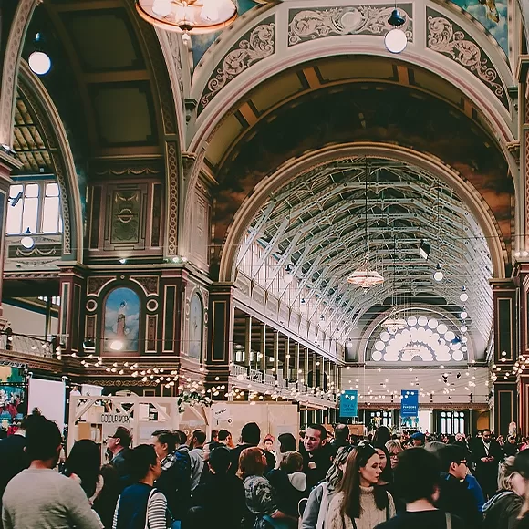 A large group of individuals congregated in a vast beautiful indoor space, with beautiful arched high ceilings.