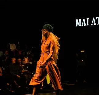 A model strutting in the middle of a runway against a dark backdrop.