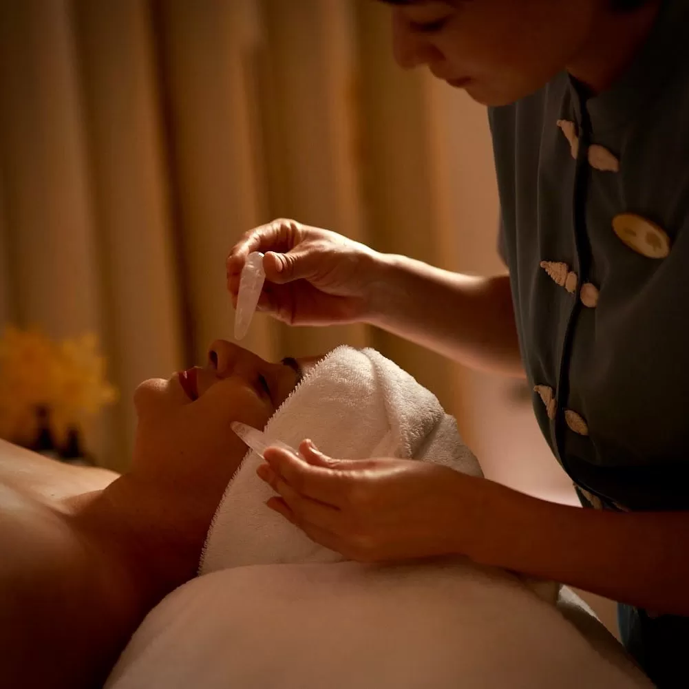 Women in robe and towels receiving luxurious facial at Raffles