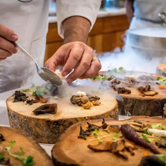 A chef is engaged in food preparation on a wooden table, highlighting the artistry and craftsmanship of cooking.