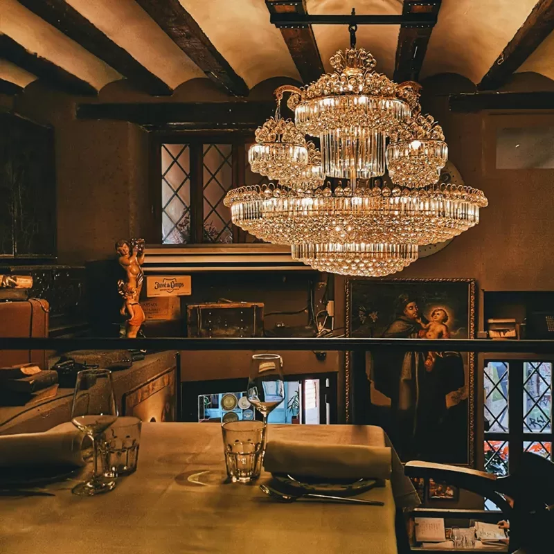 A chandelier elegantly illuminates a dining table in a sophisticated restaurant setting.