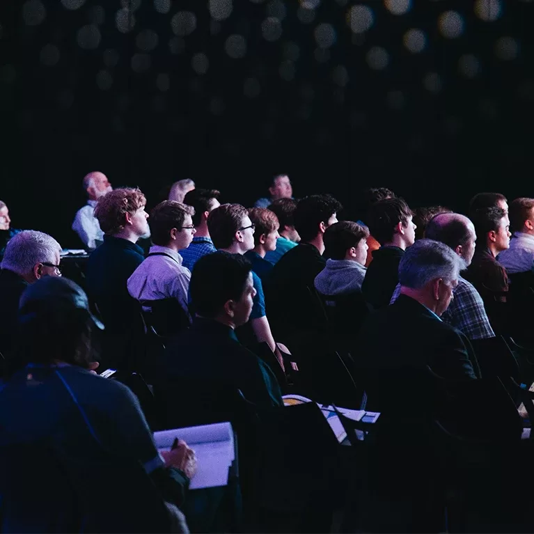 A group of people sitting in a cinema in cosy seats watching a movie screen.
