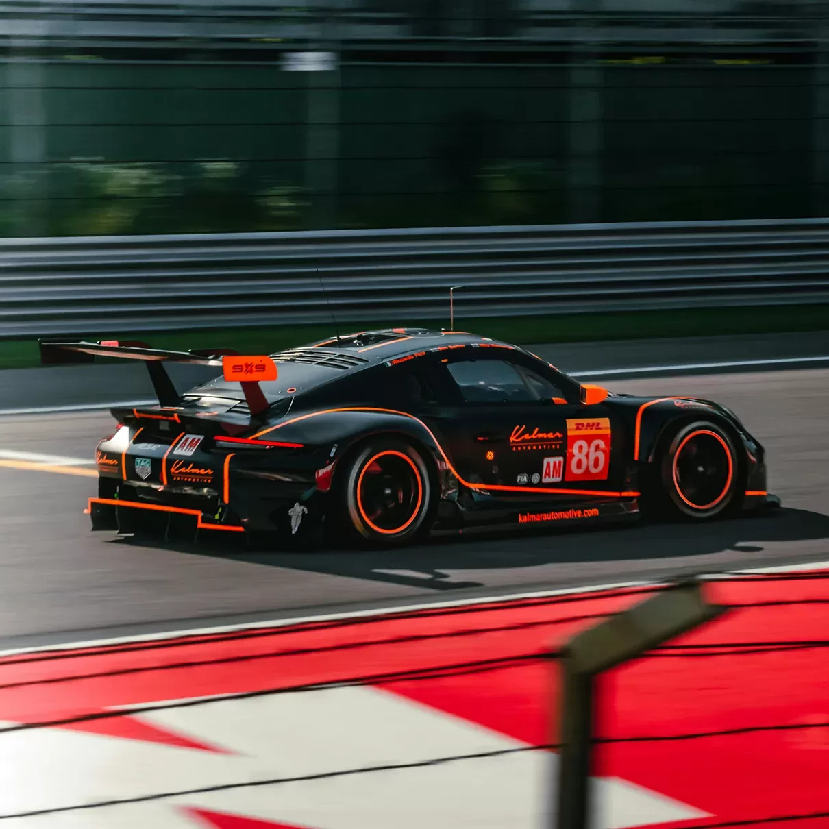 A sleek black and orange race car speeding on a track during a professional racing event.