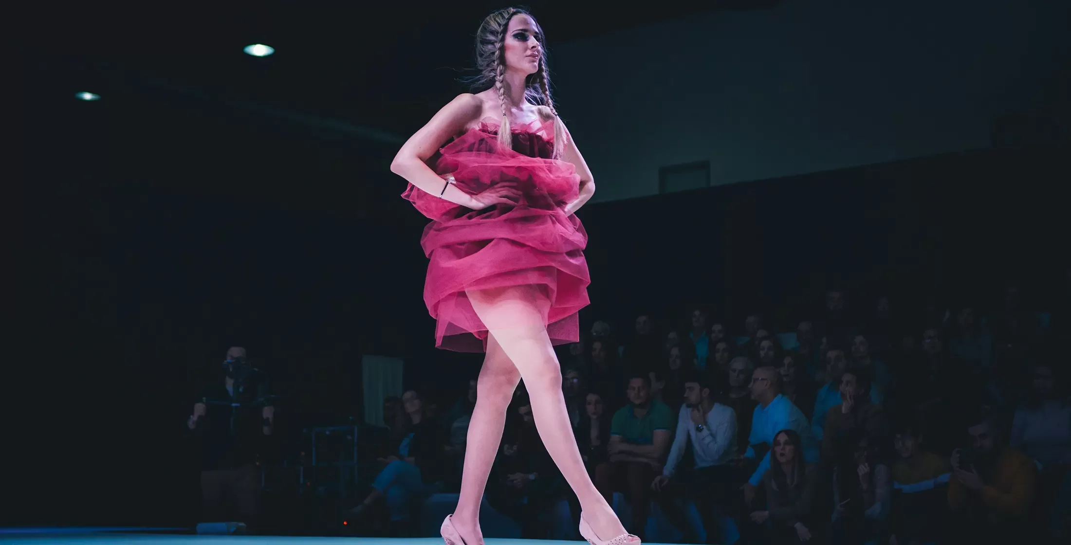 Model in pink couture dress walking down the runway