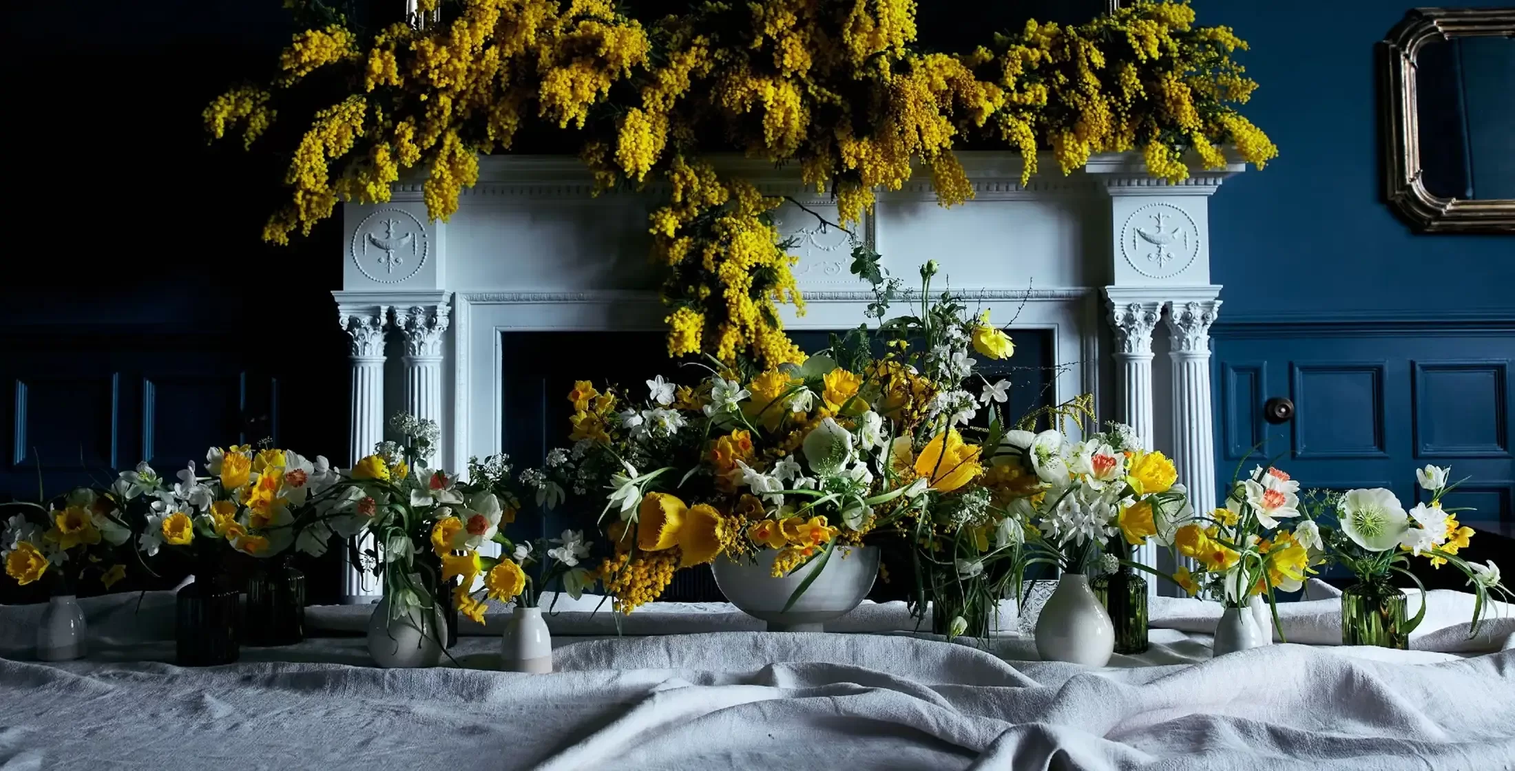 McQueens Flowers - yellow flower display over fireplace and table cloth