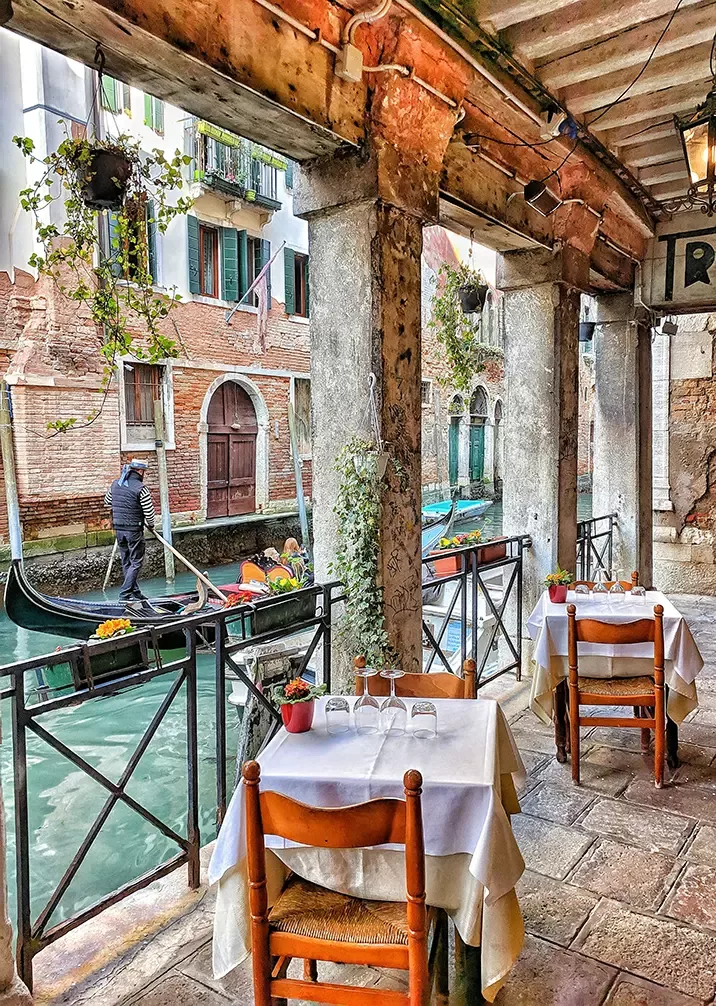 A scenic view of tables set up alongside a gondola, creating a charming outdoor dining atmosphere.