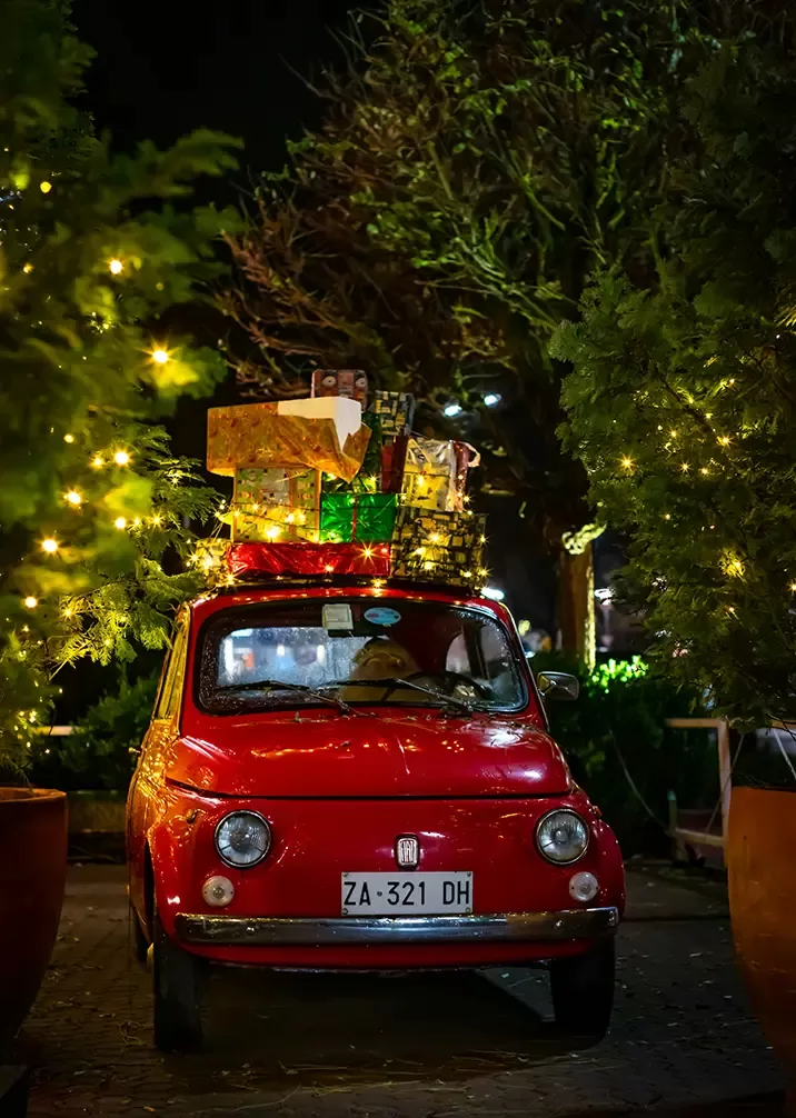 A vibrant red car featuring Christmas decorations on top, embodying the joy and celebration of the holiday season.