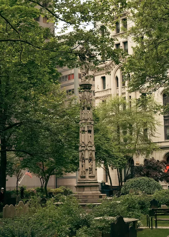 A monument surrounded by trees and benches in a serene park setting, inviting visitors to relax and reflect.