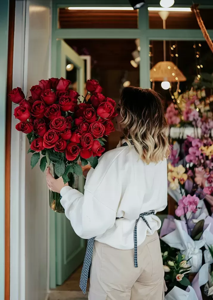 A woman gracefully holds a vibrant bouquet of red roses, showcasing their beauty and elegance.