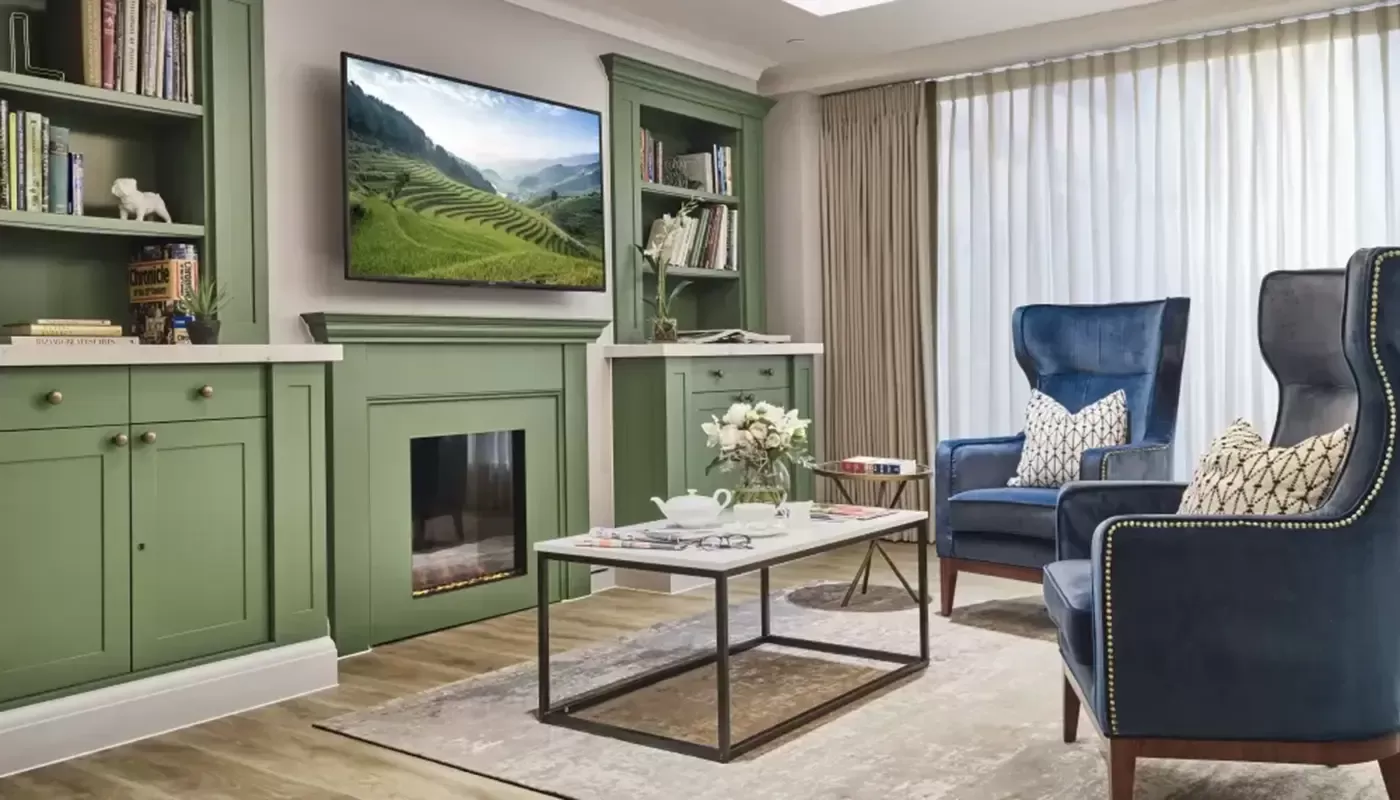 Lounge with two blue armchairs, green TV unit, bookshelf and TV