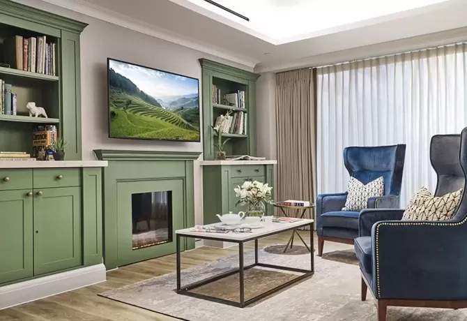 Lounge with two blue armchairs, green TV unit, bookshelf and TV