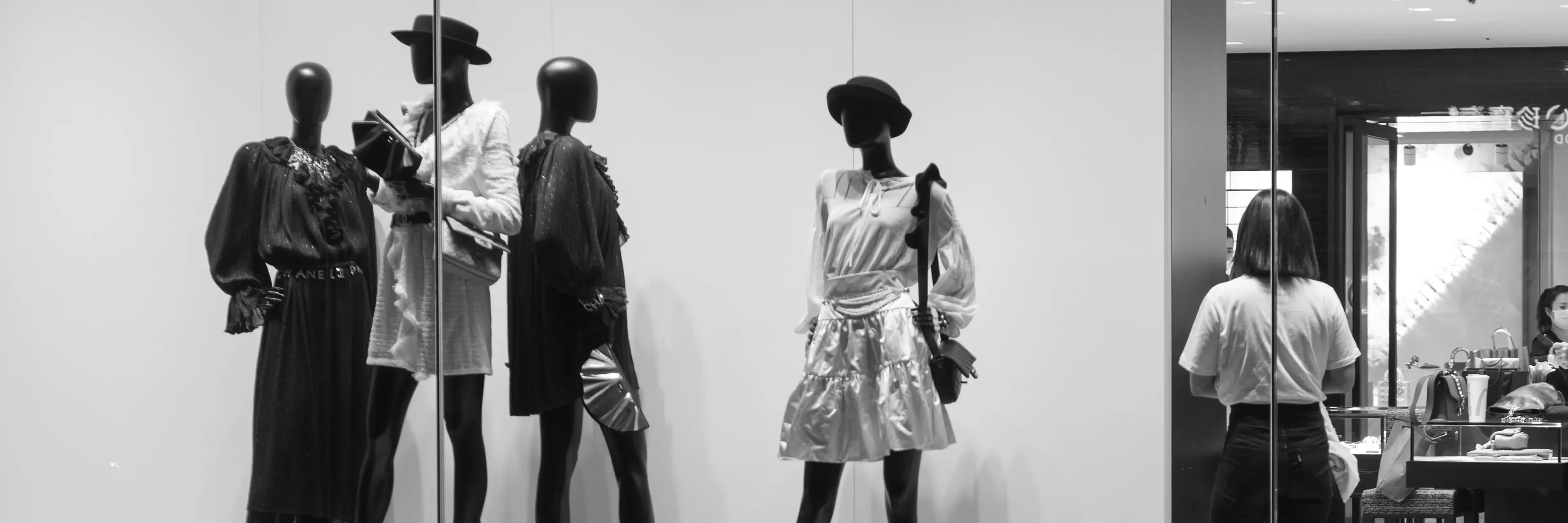 Black and white photo of window display of mannequins wearing women's fashion