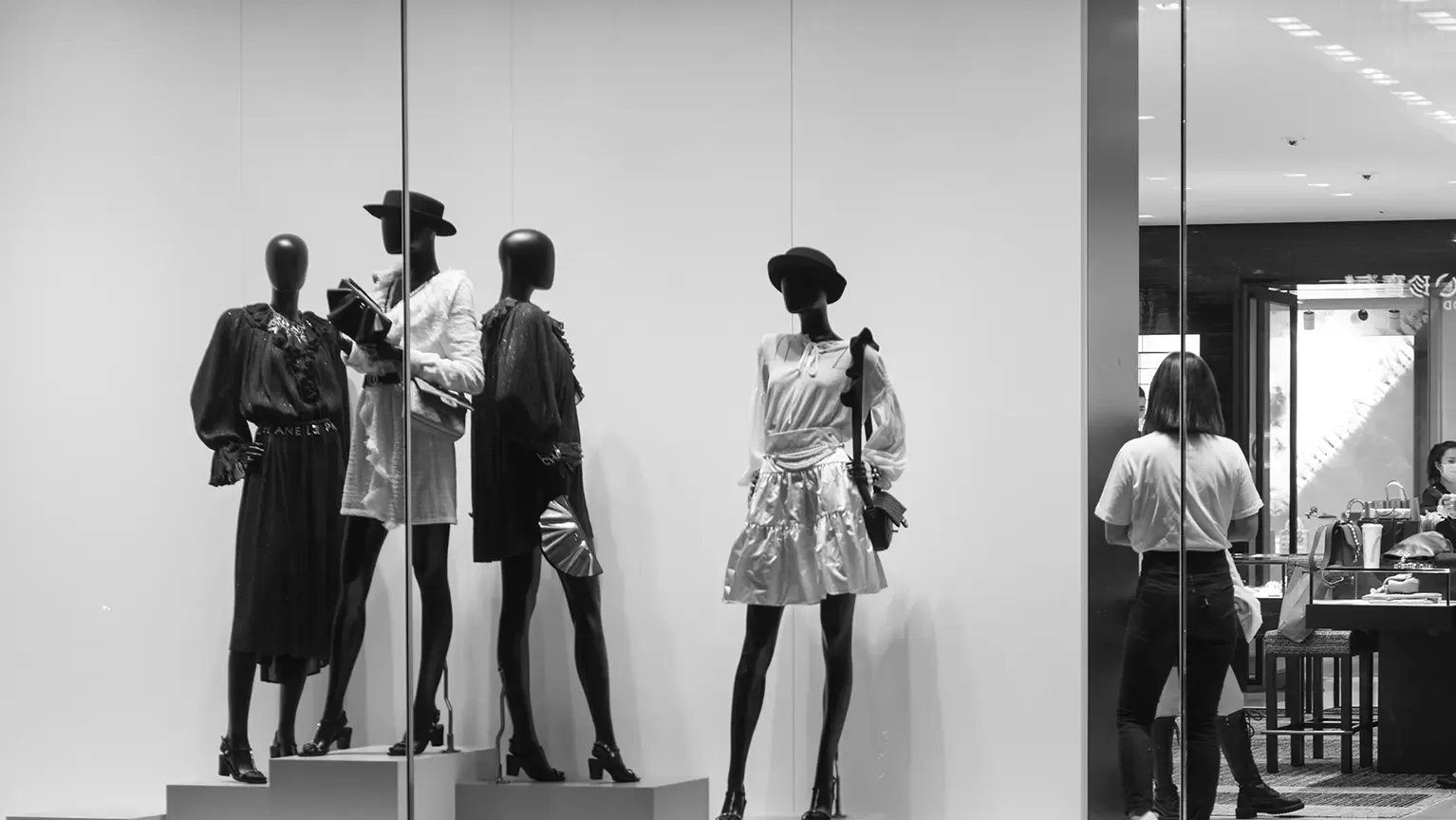 Black and white photo of window display of mannequins wearing women's fashion