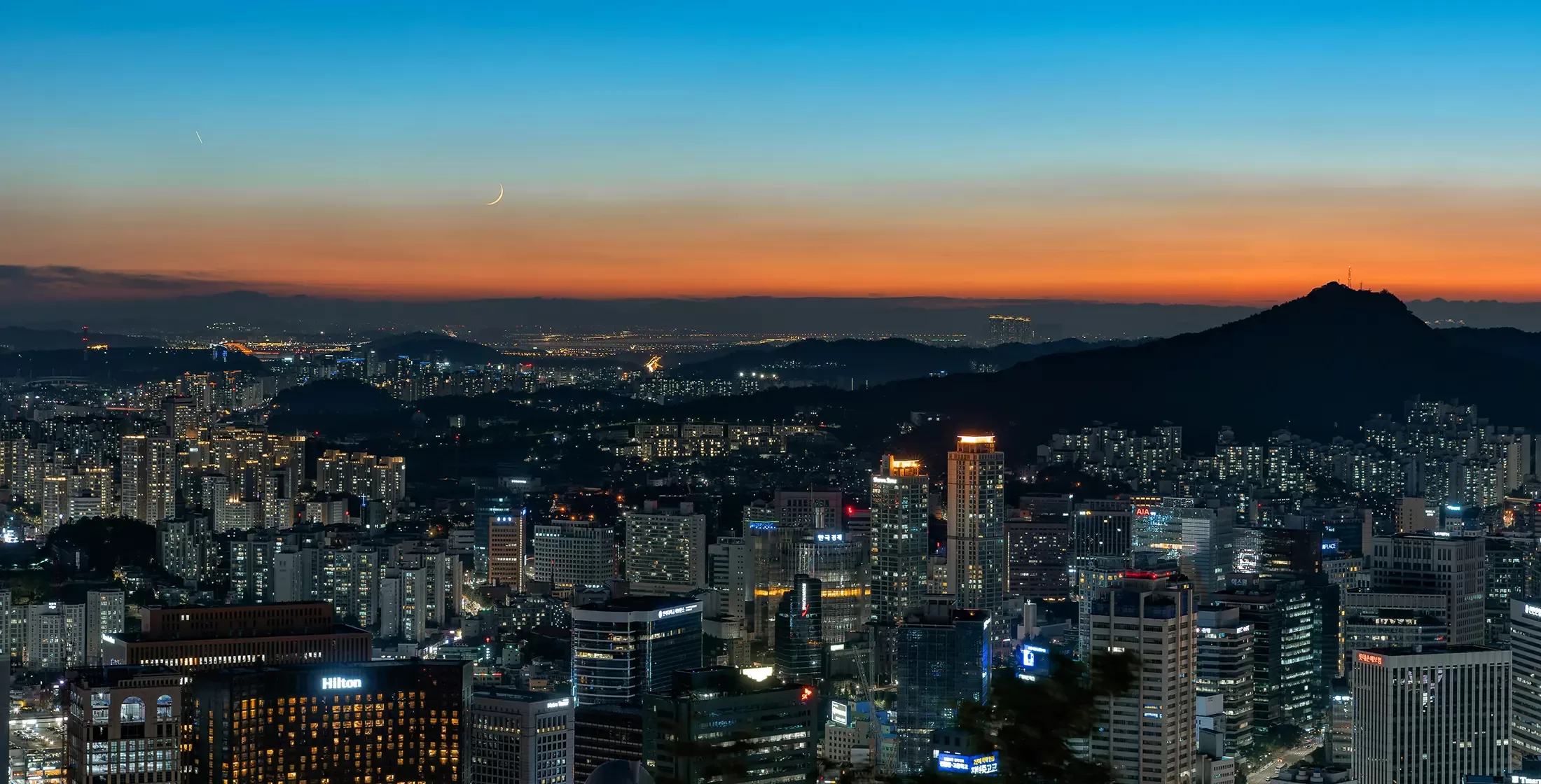 Birdseye view of lit up city of Seoul with pink night sky
