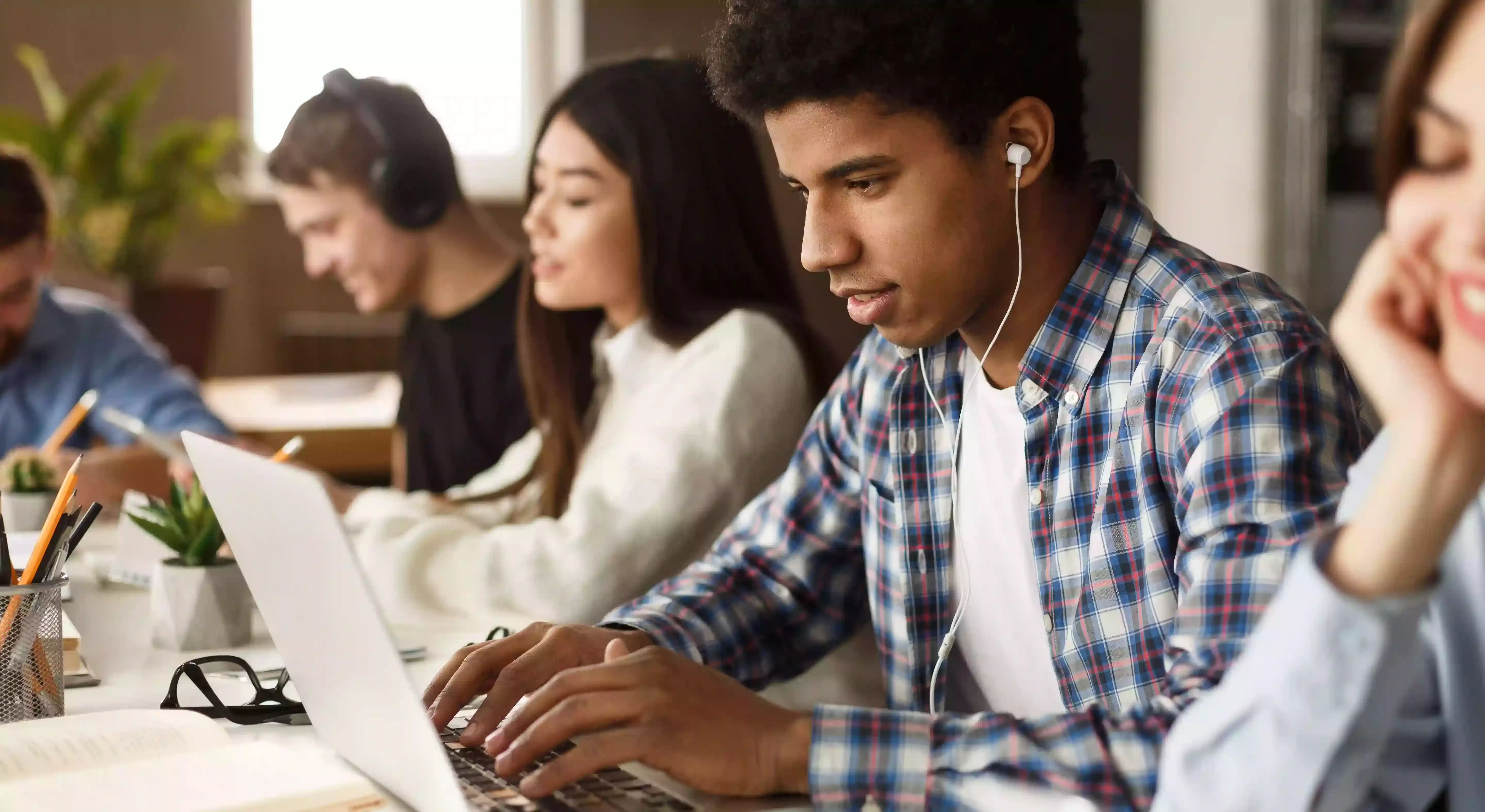 Students with headphones studying on laptops