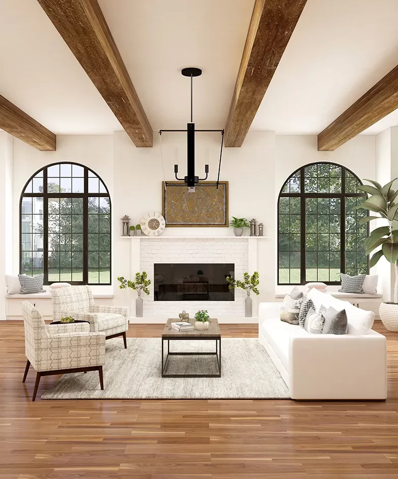A stylish living room with wooden ceiling beams, a white brick fireplace, large arched windows, and wooden flooring. There is a white sofa with gray cushions, two patterned armchairs, and a coffee table on a light area rug.