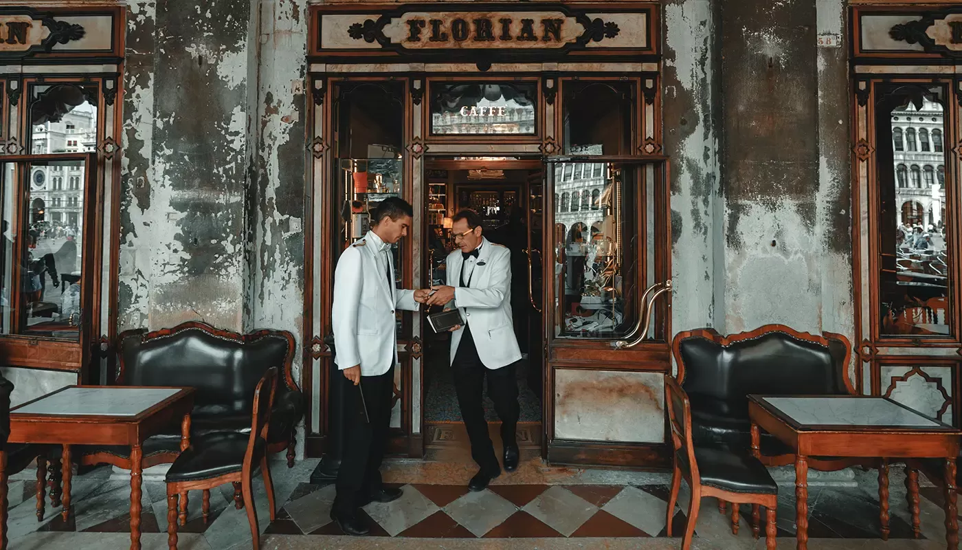 Waiters in white tuxedos shaking hands outside retro restaurant