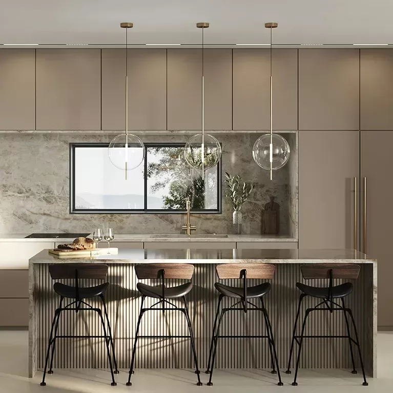 Modern kitchen with sleek beige cabinetry and marble backsplash. A large island with a ribbed front features three stylish bar stools and a countertop adorned with bread and wine glasses. Three spherical pendant lights hang above the island, and a window offers natural light.