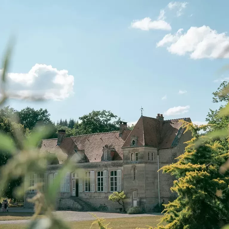 A large house surrounded by a spacious garden, nestled in the heart of a lush forest.