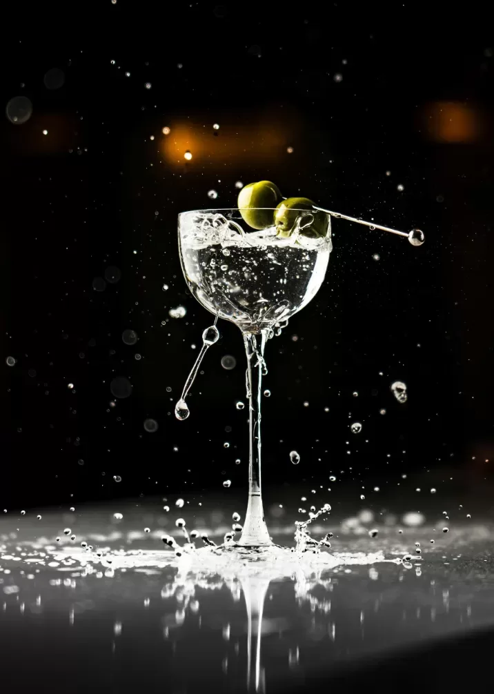A vibrant cocktail served in a glass, garnished with olives.