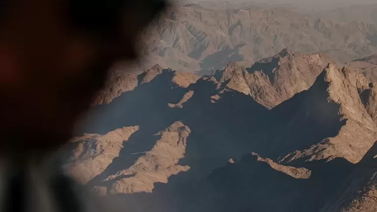 Man in a plane flying over rocky mountains in Alula, Saudi Arabia