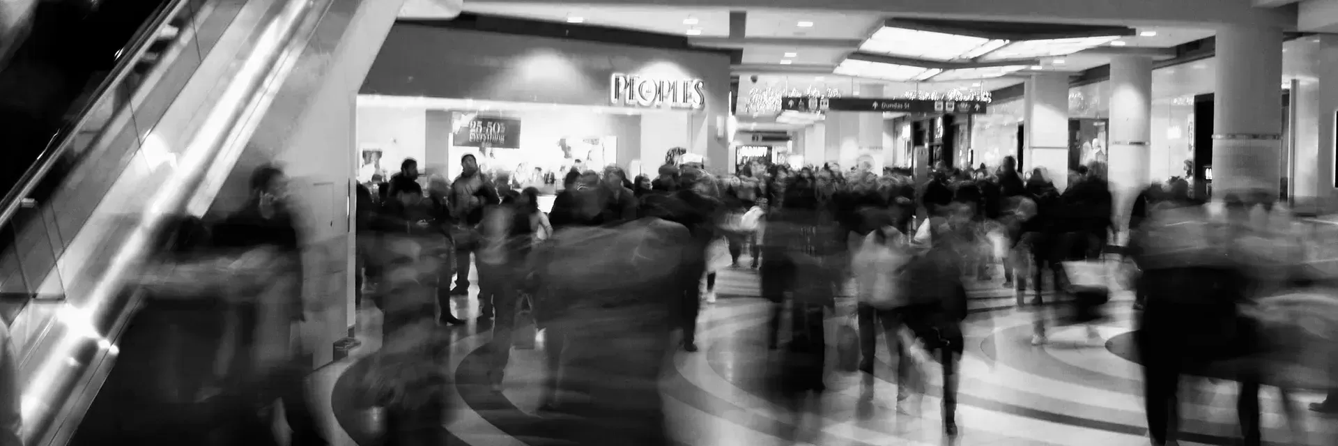 Back and white photo with long exposure of people walking through a shopping centre