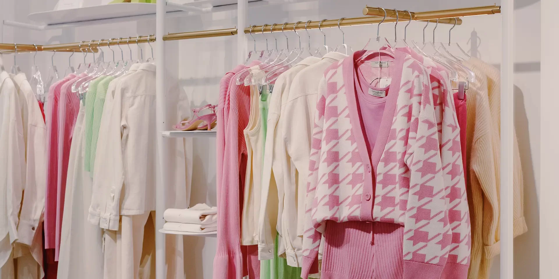Shop filled with pastel coloured women's fashion hung on white rails