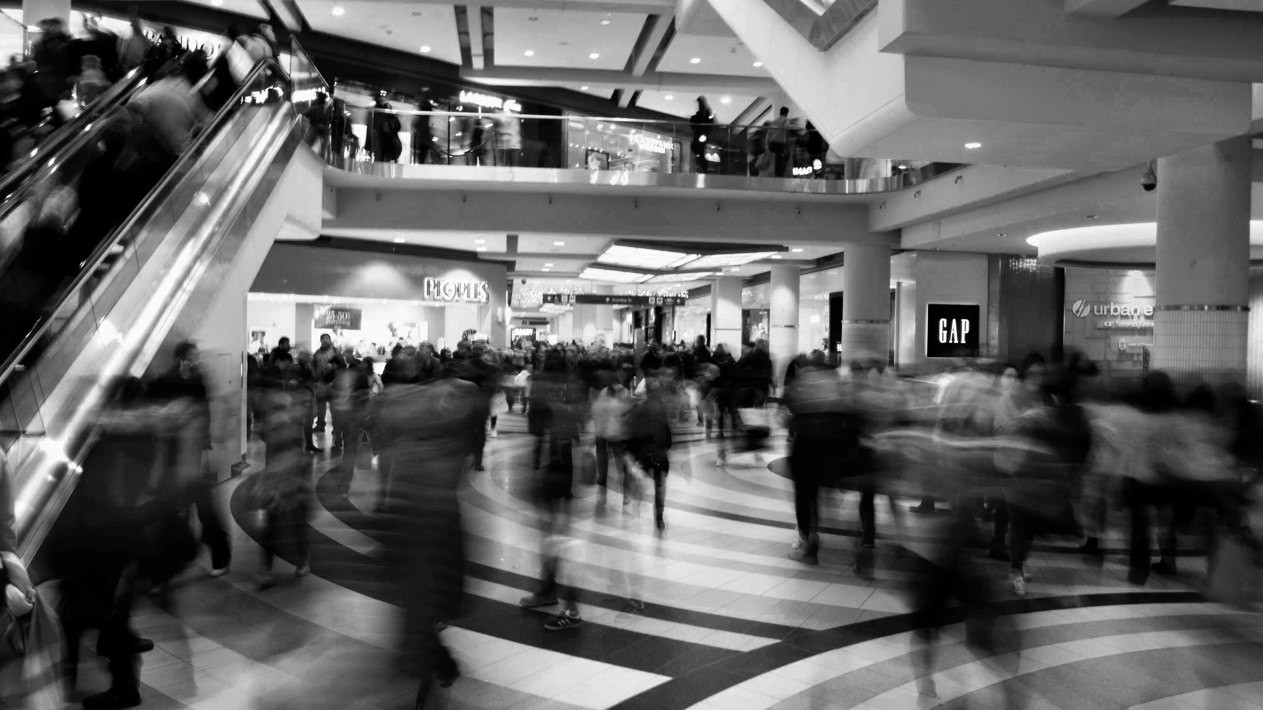 Back and white photo with long exposure of people walking through a shopping centre