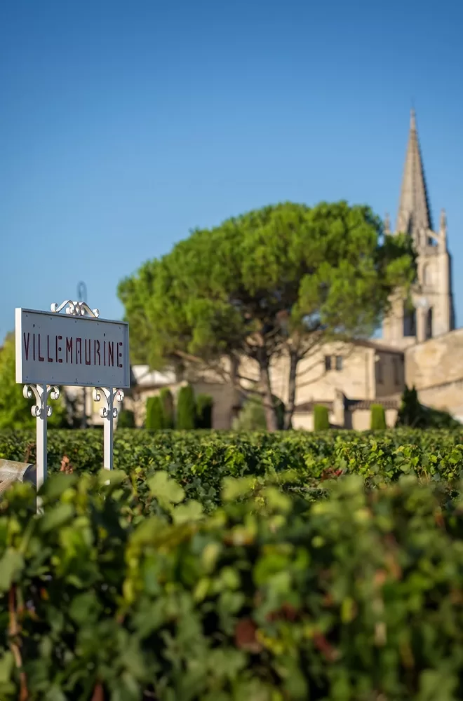 A sign reading "Villeneuve" stands prominently in front of Château Villemaurine church in Saint-Émilion.