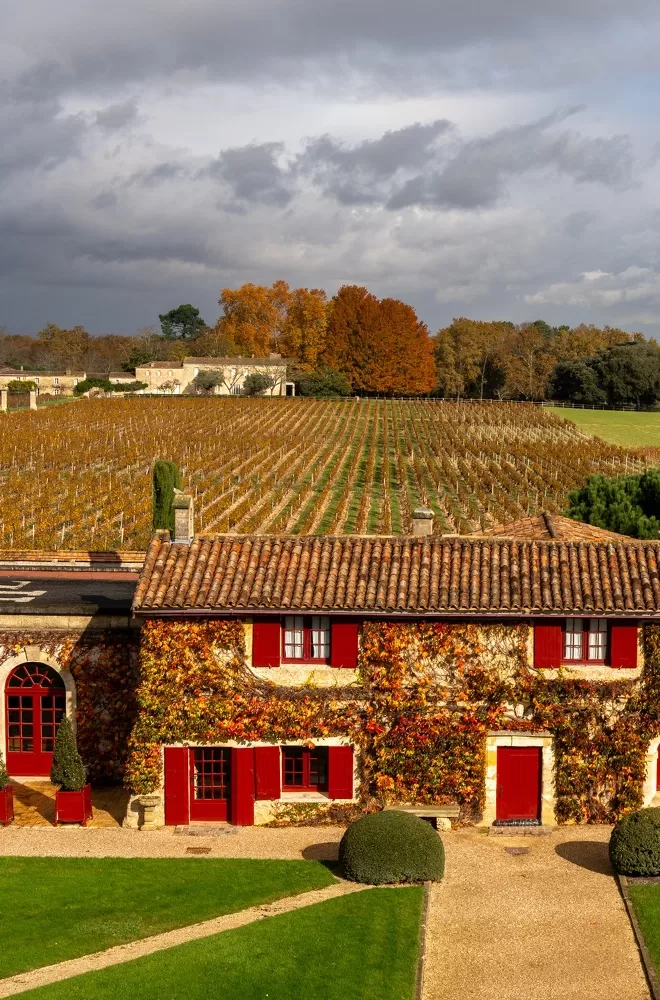 A vibrant red house with red shutters, surrounded by a picturesque vineyard at Château Smith Haut Lafitte, Pessac-Léognan.