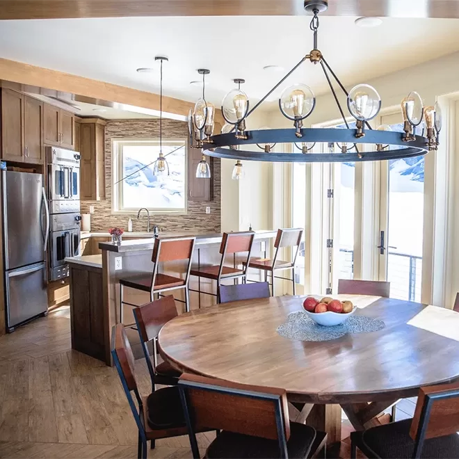 Contemporary kitchen and dining area showcasing wooden interior with exposed brick wall at Sheldon Chalet, Alaska.
