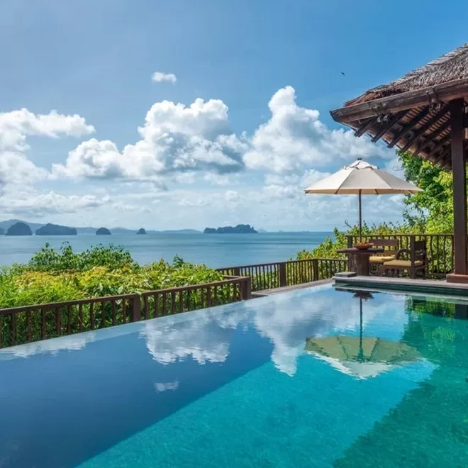 An exterior swimming pool with a view of greenery, sea and clouds at Six Senses Yao Noi, Thailand.