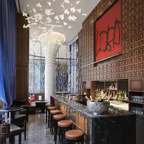 The luxurious bar interior at Canton Blue, The Peninsula London features a large, elegant painting and tall sculptural art piece, enhancing its sophisticated ambience.