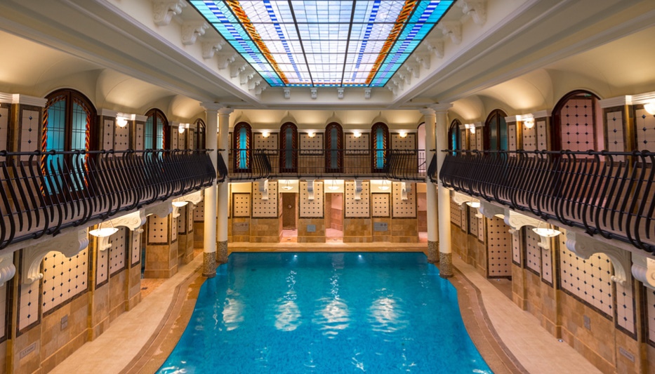 Beautiful horse shoe shaped room with balcony's over looking large blue swimming pool at Corinthia Spa, Budapest
