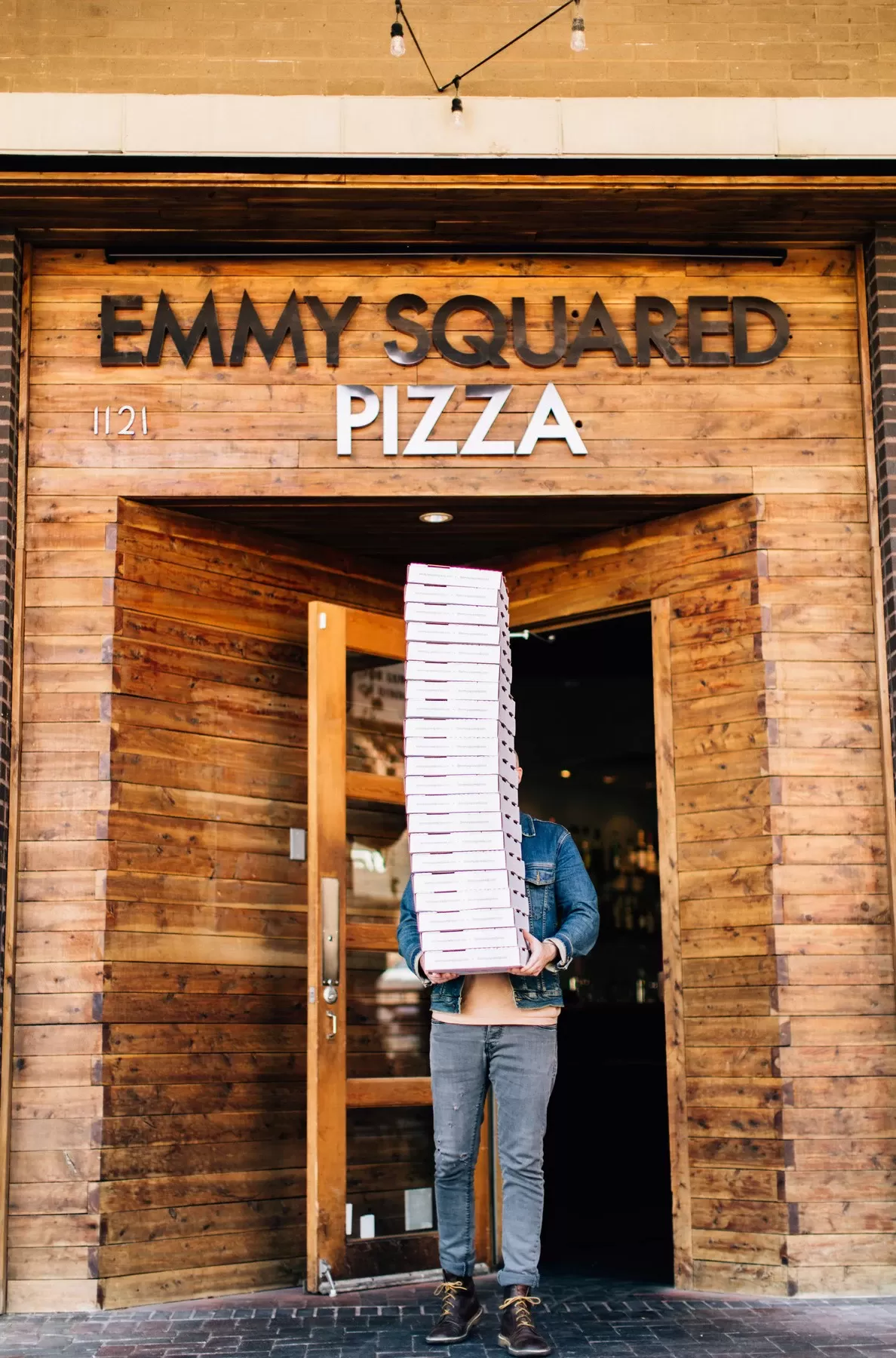 Person carrying huge stack of pizza boxes outside of Emmys Squared, Park Slope, Brooklyn, USA