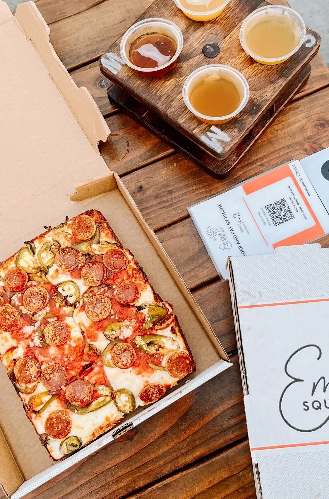 Detroit-style pizza served in a cardboard box with dips at ﻿Emmys Squared Park Slope, Brooklyn, USA
