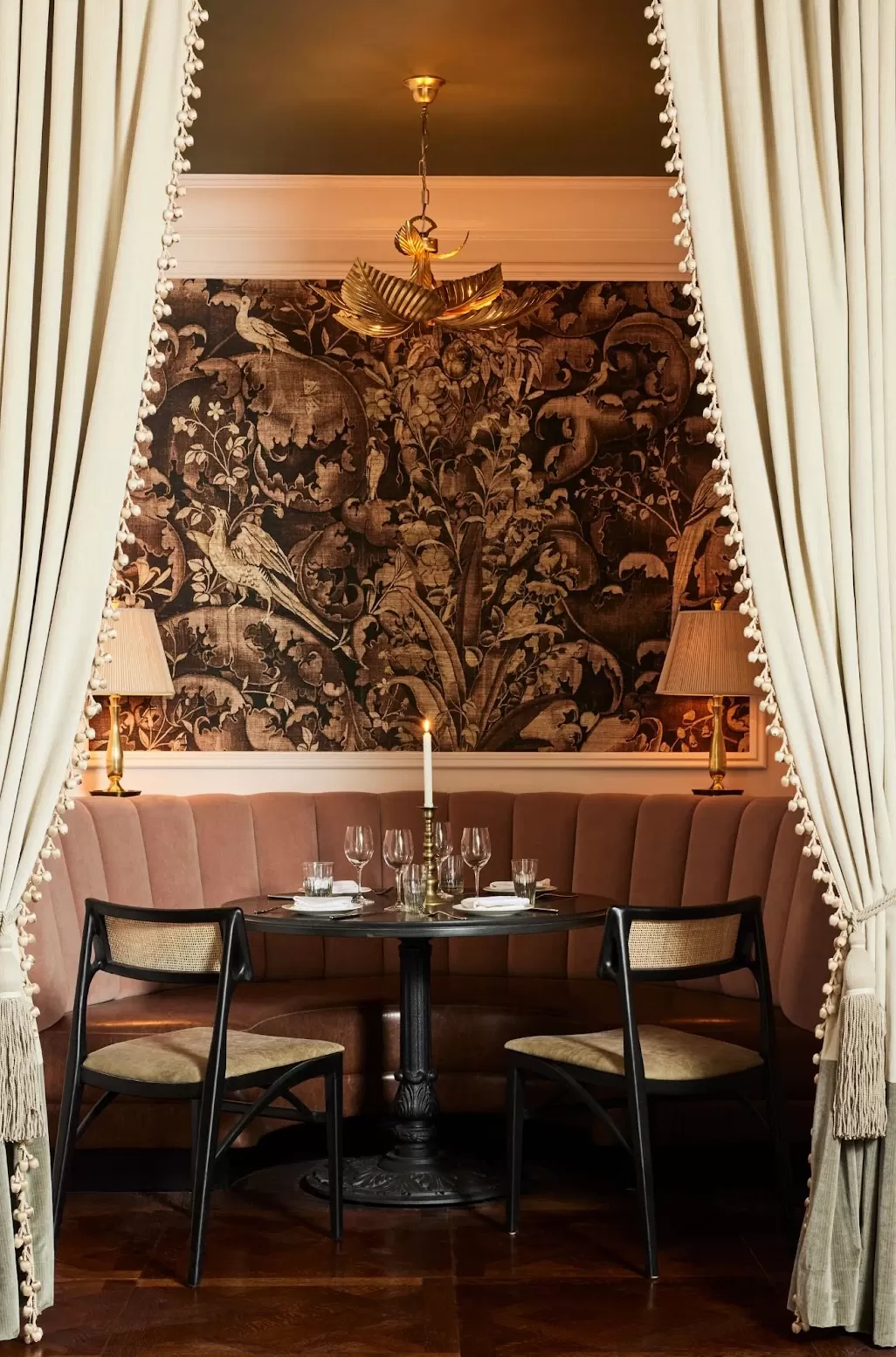 Private dining booth with pink pleated sofa and printed wallpaper at La Marchande, New York