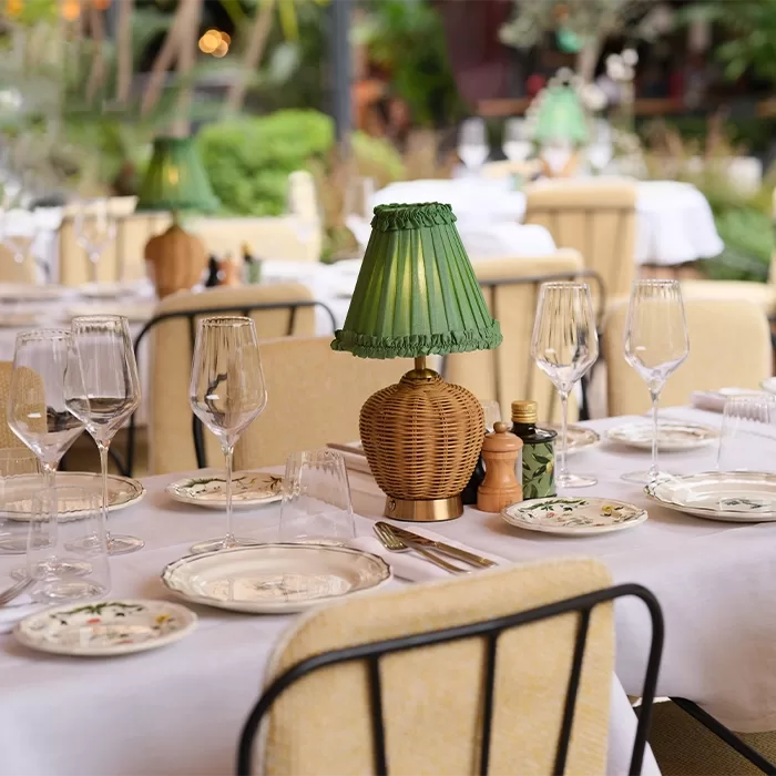 Elegant dining interior at Zeffirino restaurant in Monte Carlo, featuring exquisite cuisine and a stunning ambiance with china plates and green wicker lamp centrepiece.