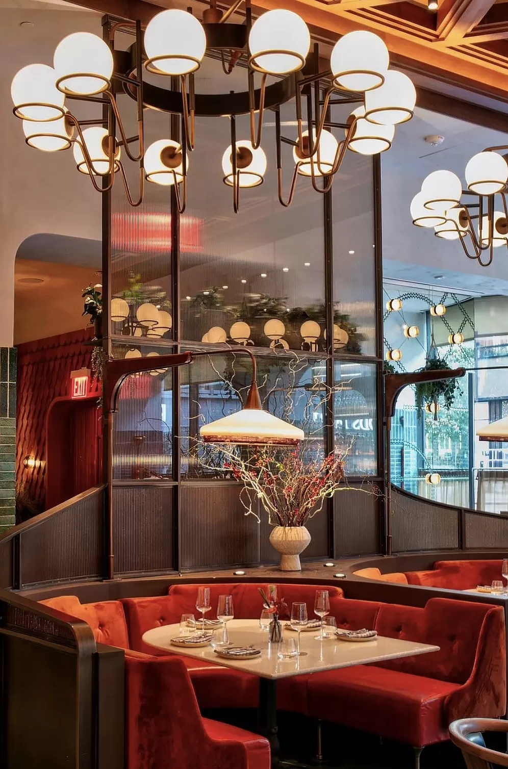 Private dining booth with red sofas accompanied by flowers and hanging lights at Eastern Mediterranean restaurant Zou Zou's, Hudson Yards, New York