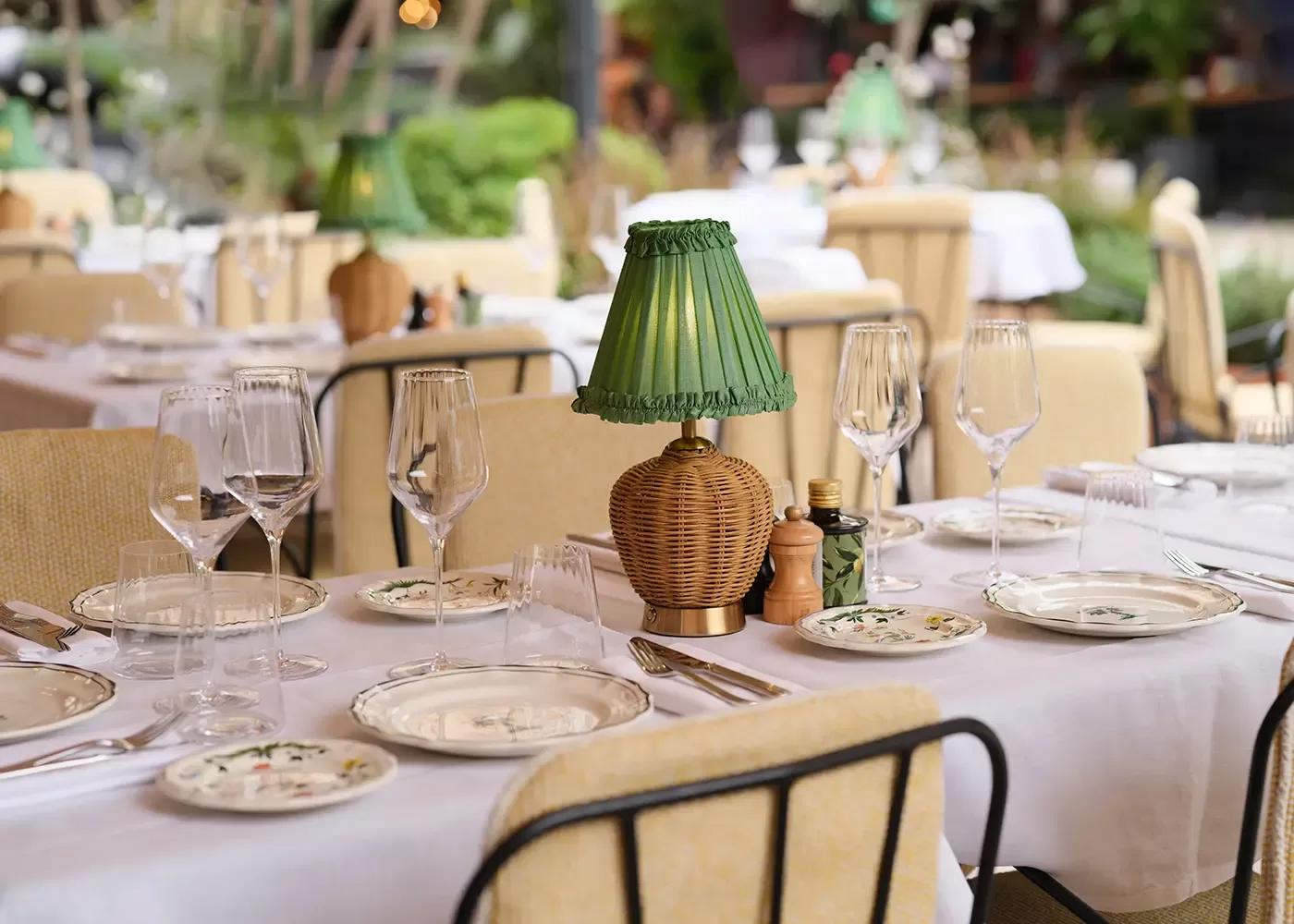 Elegant dining interior at Zeffirino restaurant in Monte Carlo, featuring exquisite cuisine and a stunning ambiance with china plates and green wicker lamp centrepiece.
